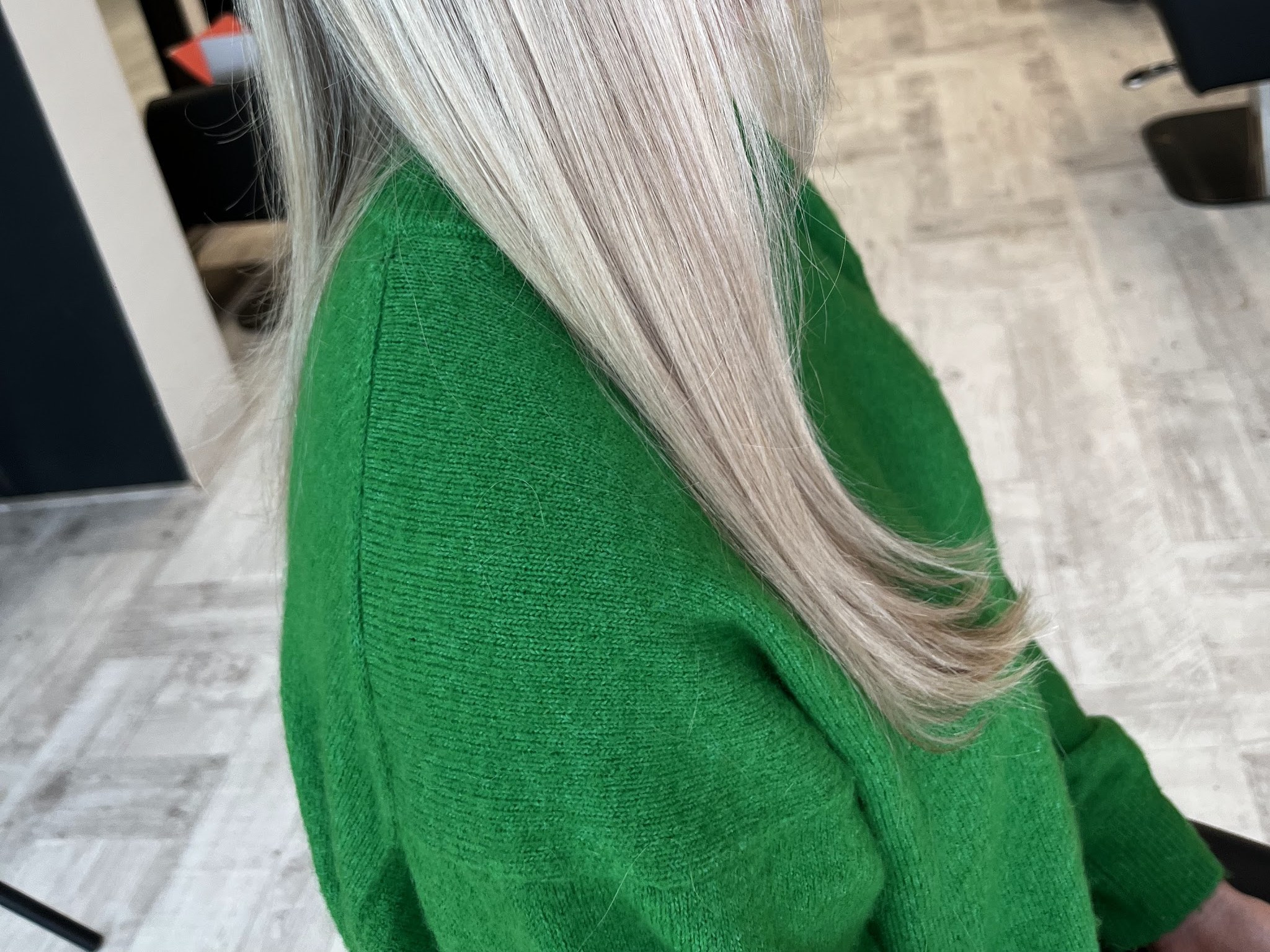 Lang blond haar met lichte highlights over een groene trui